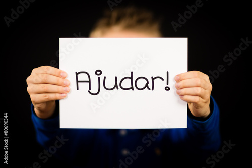 Child holding sign with Portuguese word Ajudar - Help