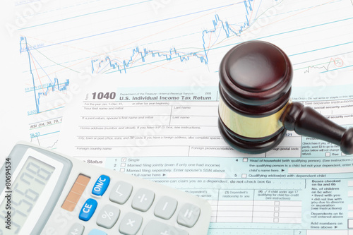 Wooden judge's gavel and calculator over 1040 US Tax form photo