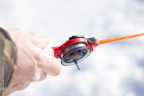 hand holding small red bait for winter fishing