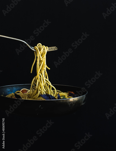 Hot spaghetti with tomatoes in cooking pan and fork