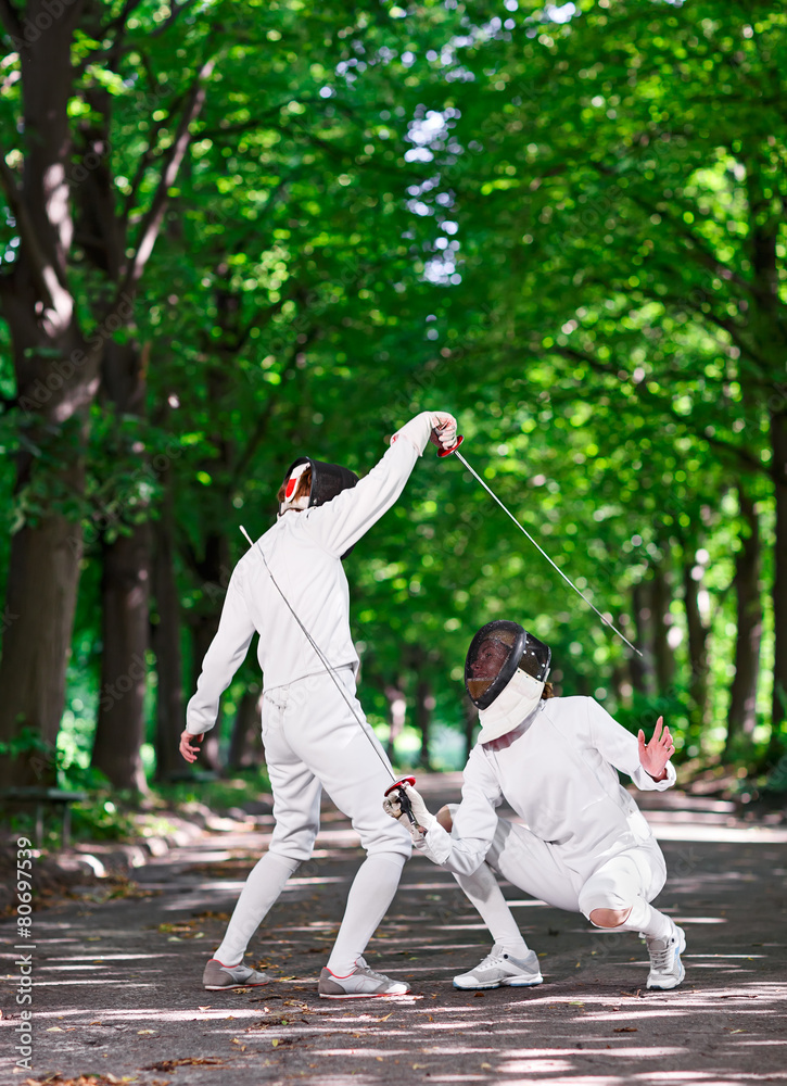 Obraz premium Two rapier fencers women fencing on park path