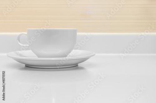 A white ceramic cup with saucer on counter top