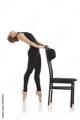 Pretty young ballerina posing with chair. Isolated on white