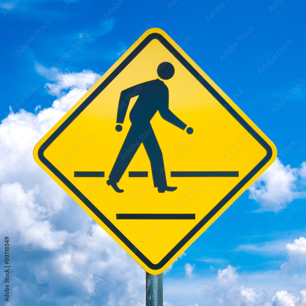 Yellow crossing traffic sign and a cloudy sky Yellow crossing traffic sign and a cloudy sky