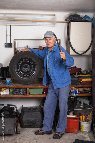 Senior worker with a tire in garage