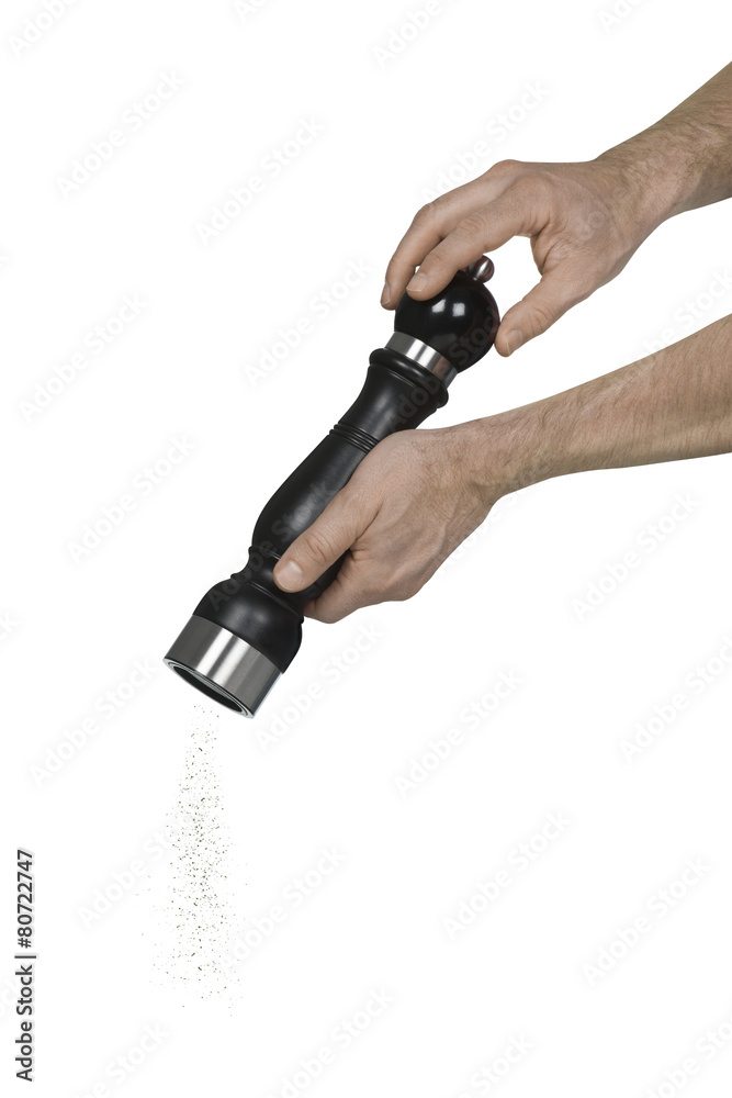 Two caucasian male hands using a pepper grinder Two caucasian male hands using a pepper grinder