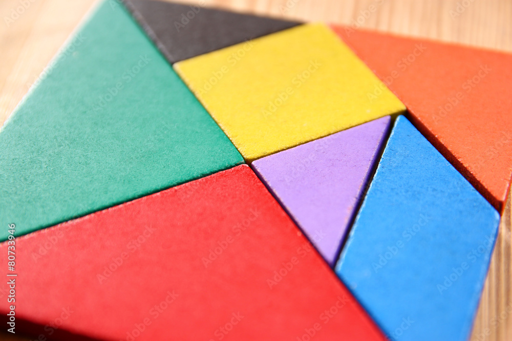 a missing piece in a square tangram puzzle, over wooden table. a missing piece in a square tangram puzzle, over wooden table.