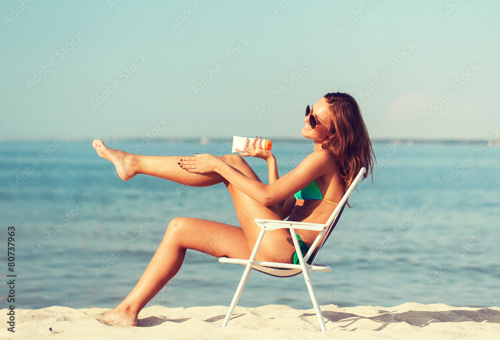 smiling young woman sunbathing in lounge on beach smiling young woman sunbathing in lounge on beach