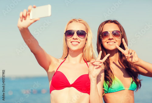 two smiling women making selfie on beach