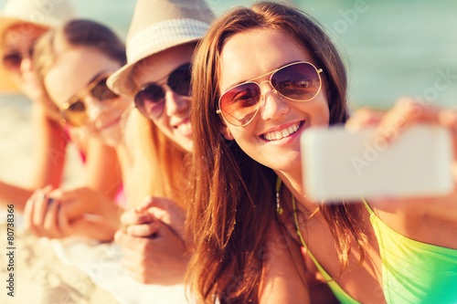 close up of smiling women with smartphone on beach