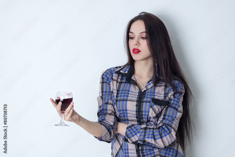 Brunette holding a glass of wine and looking at it Brunette holding a glass of wine and looking at it