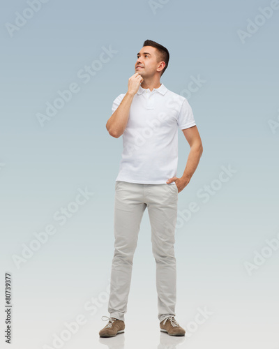 smiling man with hands in pockets looking up