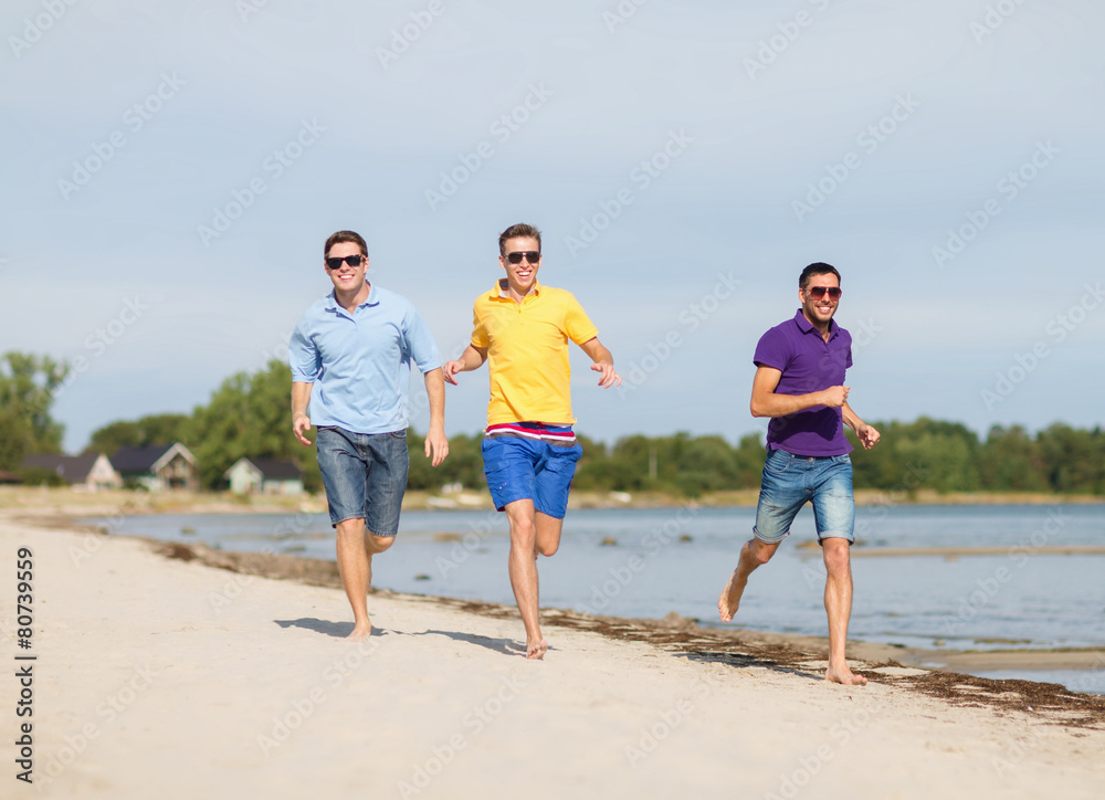 smiling friends in sunglasses running along beach smiling friends in sunglasses running along beach