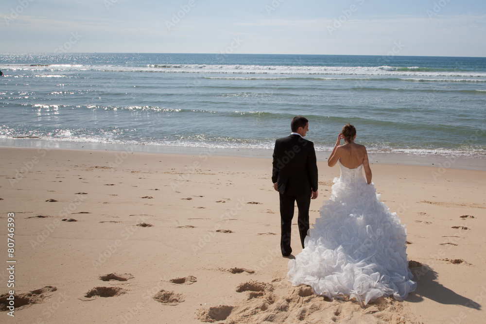 A rear view of a beautiful couple on the beach in wedding dress A rear view of a beautiful couple on the beach in wedding dress