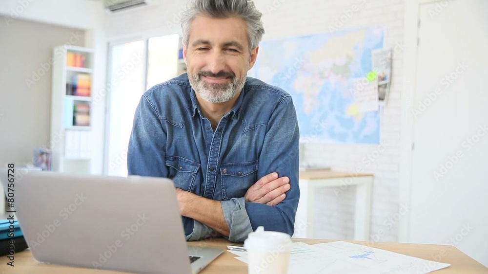 Mature man working on laptop in school office Mature man working on laptop in school office