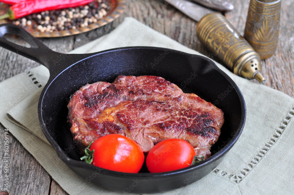 Juicy beef steak in a frying pan Juicy beef steak in a frying pan
