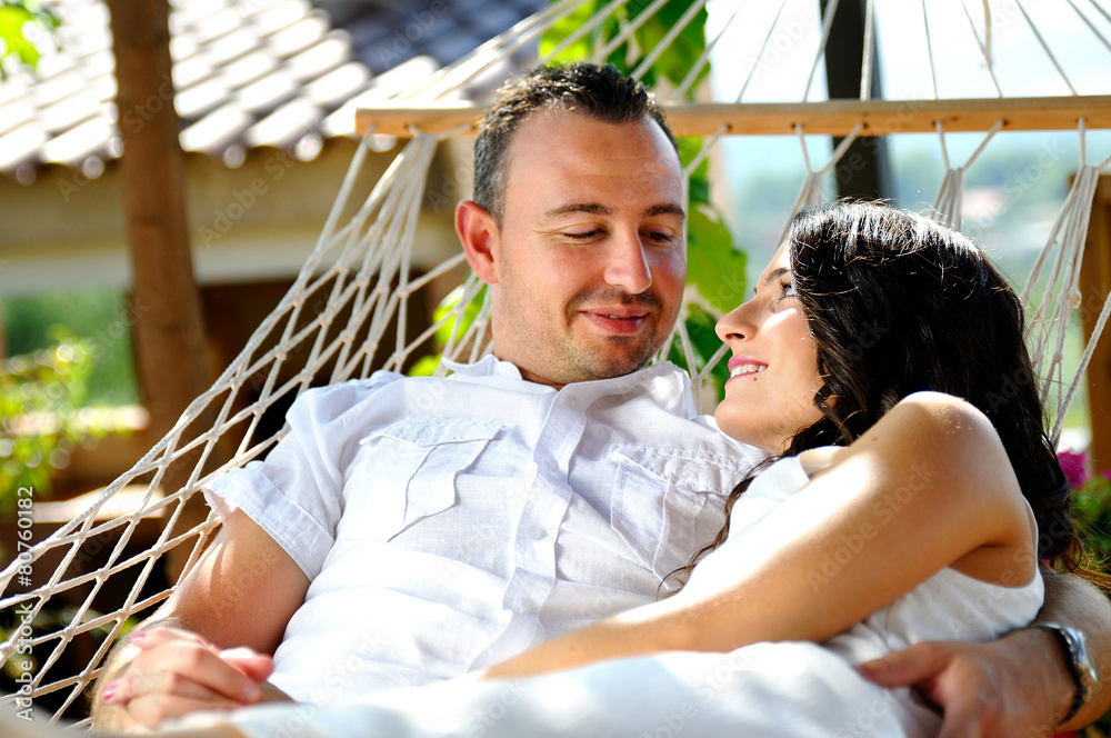 Young couple on a rope hammock in a cottage front view