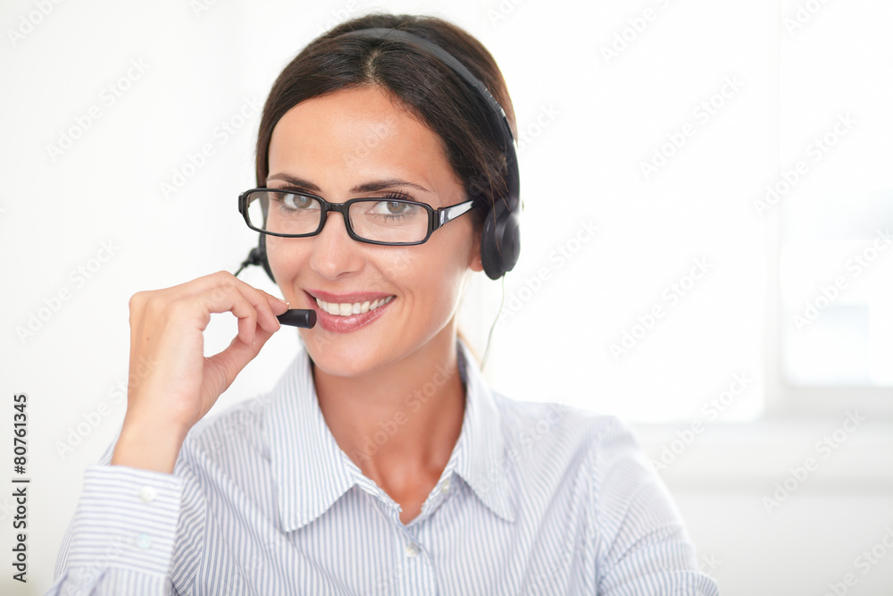 Charming secretary conversing on her headphones Charming secretary conversing on her headphones