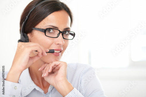 Pretty adult employee conversing on headphones