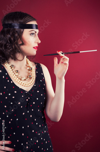 beautiful retro woman holding mouthpiece against wine red backgr