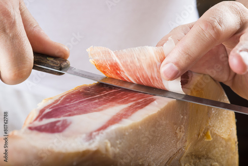 Profesional cortando lonchas de jamón serrano a cuchillo