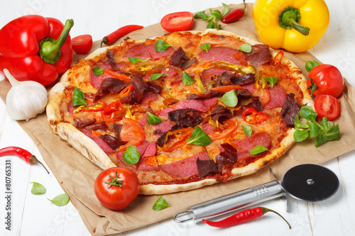 Pizza with salami and ham on wooden table