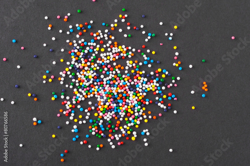 Colorful round sprinkles spilled on black background, isolated
