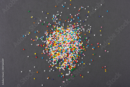 Colorful round sprinkles spilled on black background, isolated