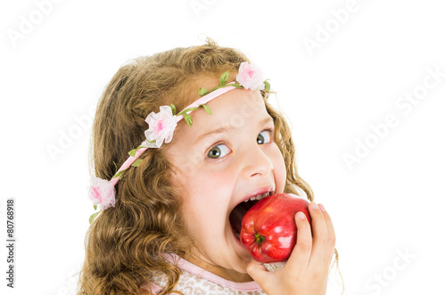 Beautiful healthy little curly girl enjoying eating a red pepper
