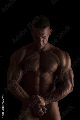 Bodybuilder posing isolated on black. © Eskymaks