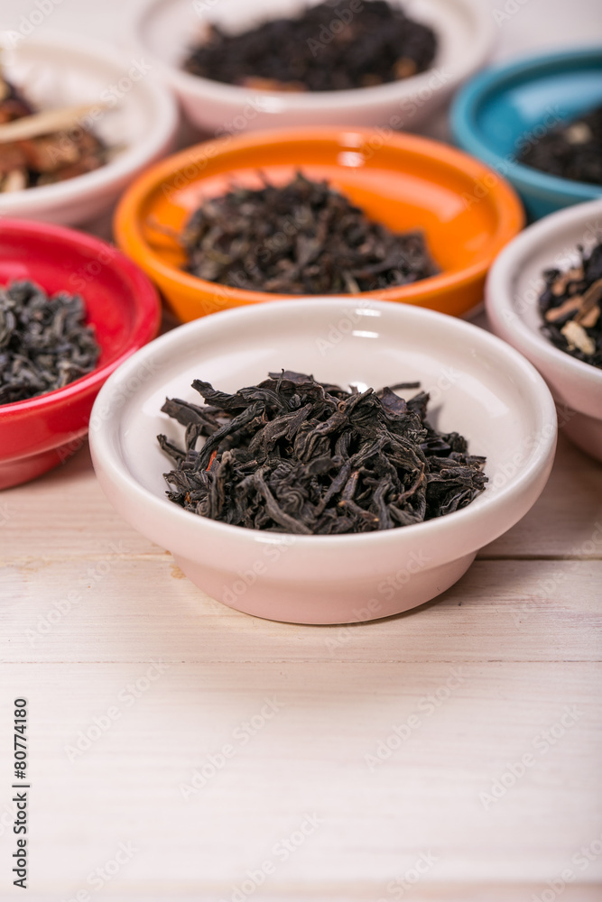 assortment of dry tea in small bowl, on wooden background assortment of dry tea in small bowl, on wooden background