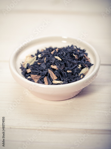 Bowl of dried green tea leaves on wooden background
