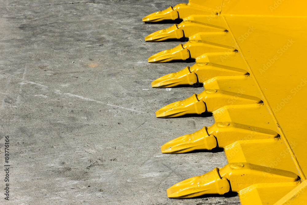 Foto de Big yellow bucket scoop on rough concrete ground. do Stock