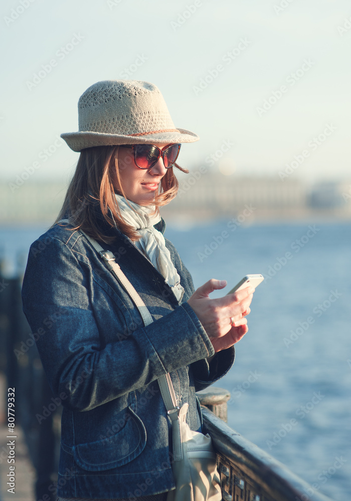 Beautiful woman in hat and scarf with mobile phone in the city