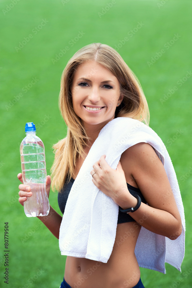 Young smiling blond woman with towel and water bottle Young smiling blond woman with towel and water bottle