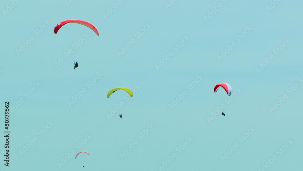 Four Paragliders Slowly Flying In The Blue Sky Four Paragliders Slowly Flying In The Blue Sky