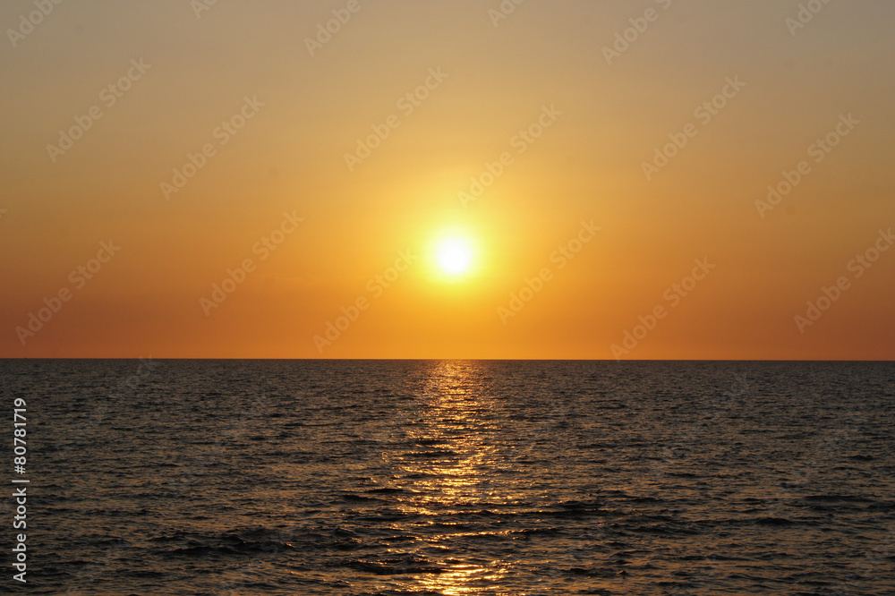 blue sea and sky with the sun at dusk