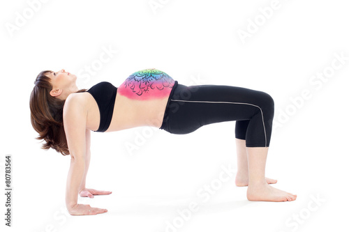 Woman with painted belly doing yoga exercise