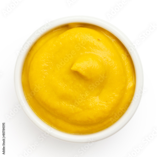 Fototapeta American yellow mustard in round dish from above on white.