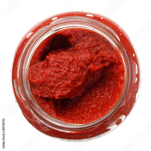 Open glass jar of tomato paste. Isolated from above.