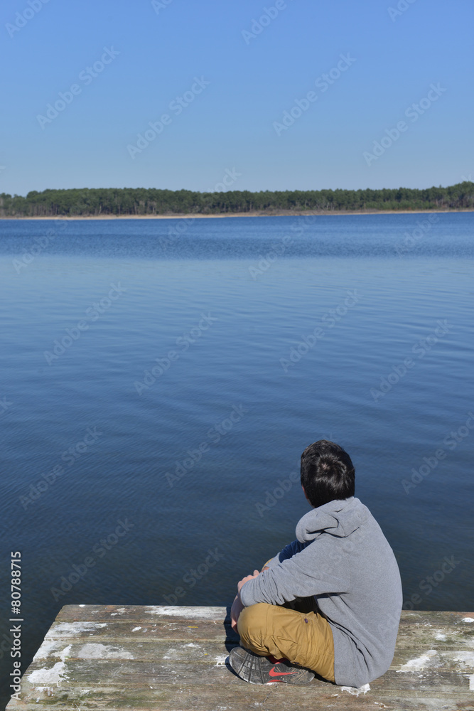 Fototapeta premium Young boy sitting on a thrown Lake