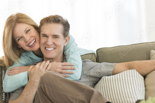 Happy Woman Embracing Man On Sofa At Home