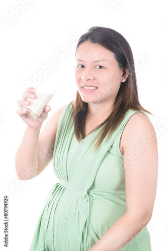 Pregnant Woman holding her pregnant belly and get a glass of mil