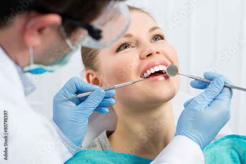Male dentist examining patient teeth before oral operation