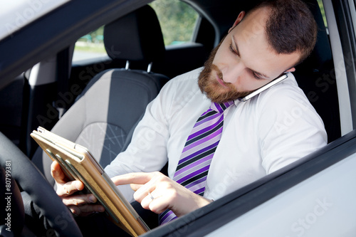 Business man working with tablet and phone in car