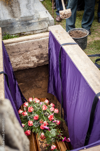 Mourners staying by the opened grave, burrying at a cemetery