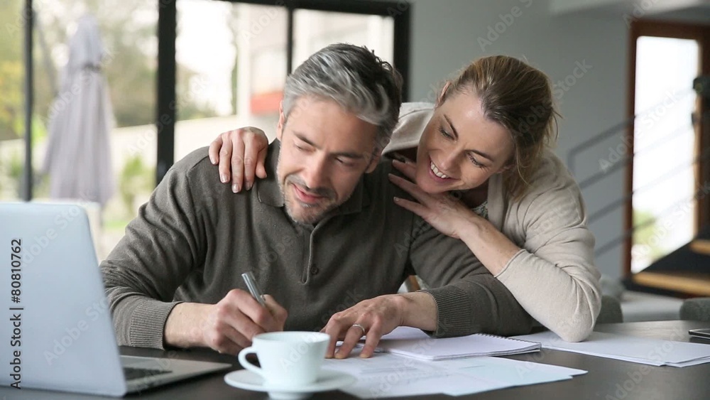 Woman embracing man while working on latptop at home