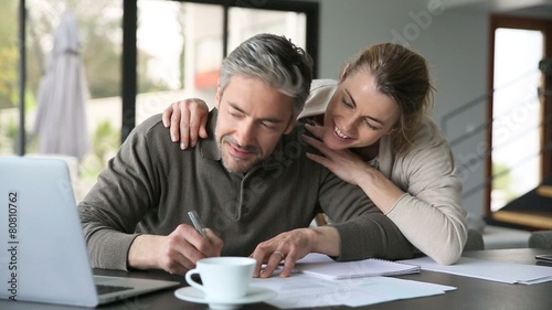 Woman embracing man while working on latptop at home photo