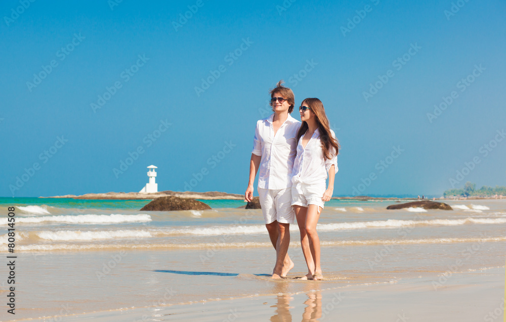 happy young couple in white clothes having fun on tropical beach
