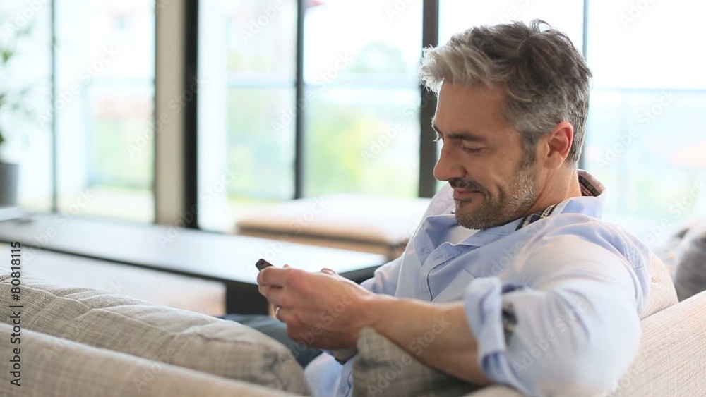 Mature man sending message with smartphone